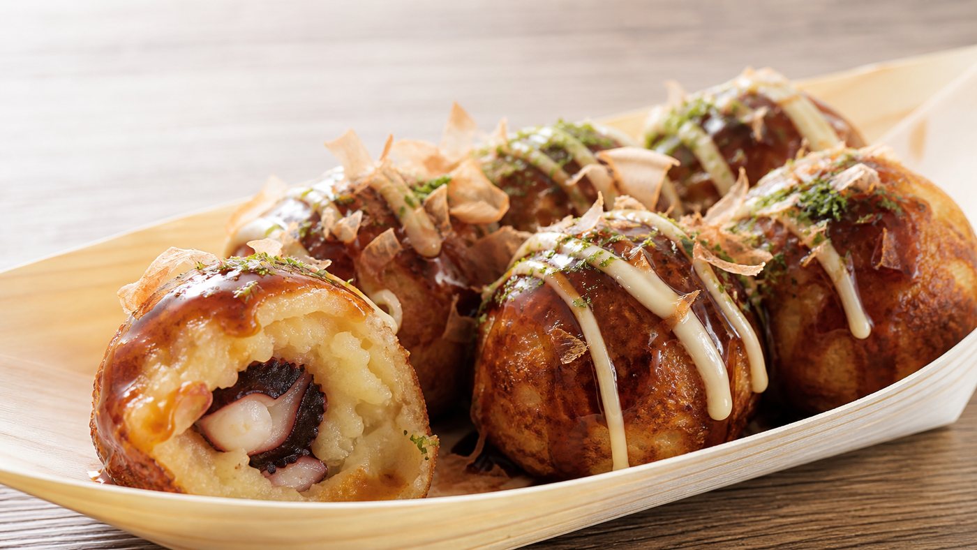 Close-up of takoyaki with sauce, mayonnaise, bonito flakes, and aonori