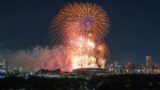 Final fireworks burst over a central Tokyo skyline and sports venue silhouette.