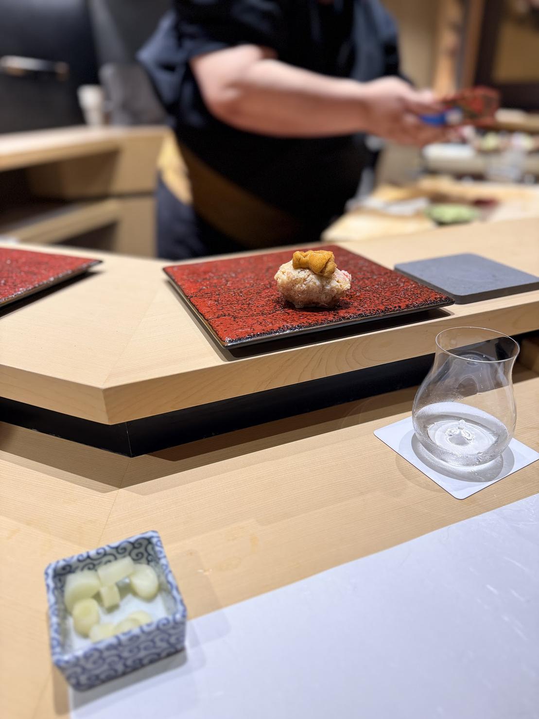 Snow crab and sea urchin nigiri served on a red lacquer plate at Zoroku Yuzan in Roppongi