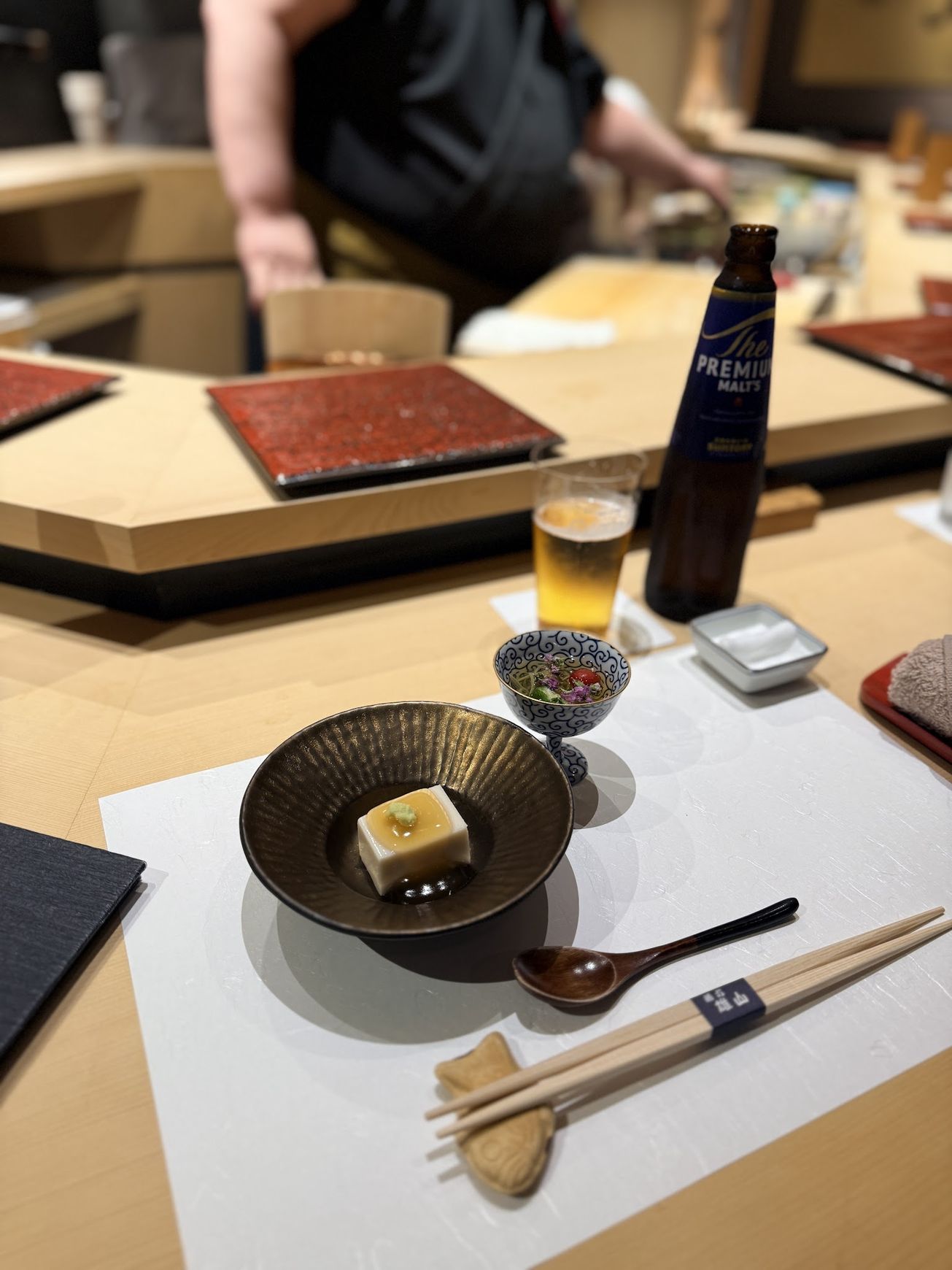 House-made sesame tofu topped with junsai water shield in a dark bowl