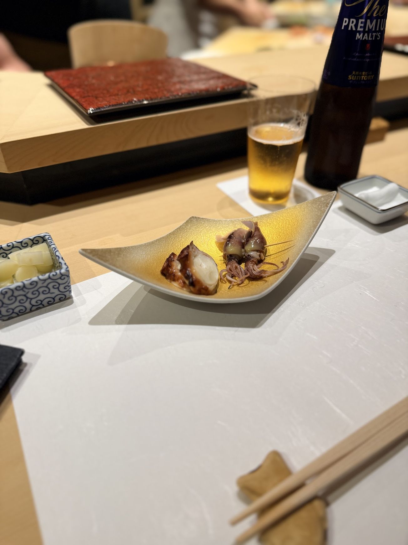 Tender simmered octopus and firefly squid on a gold leaf-shaped plate