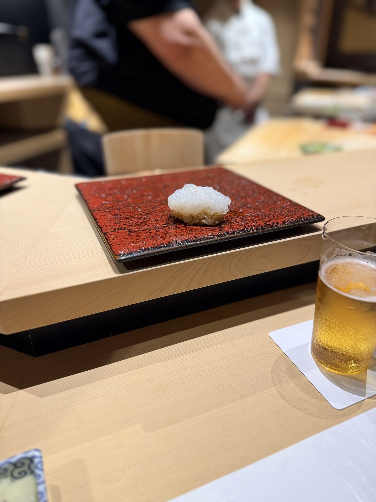 Translucent bigfin reef squid nigiri on a red lacquer plate