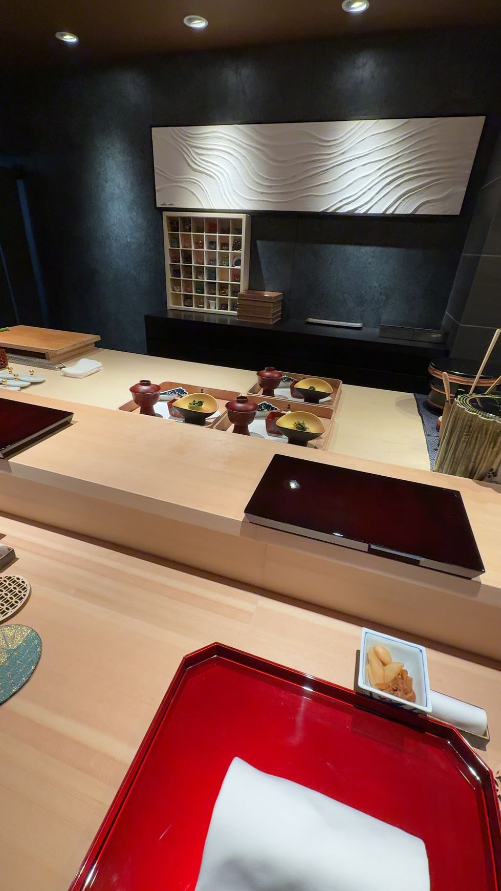Hinoki cypress counter and white wave-motif wall art inside Sushi Kensuke