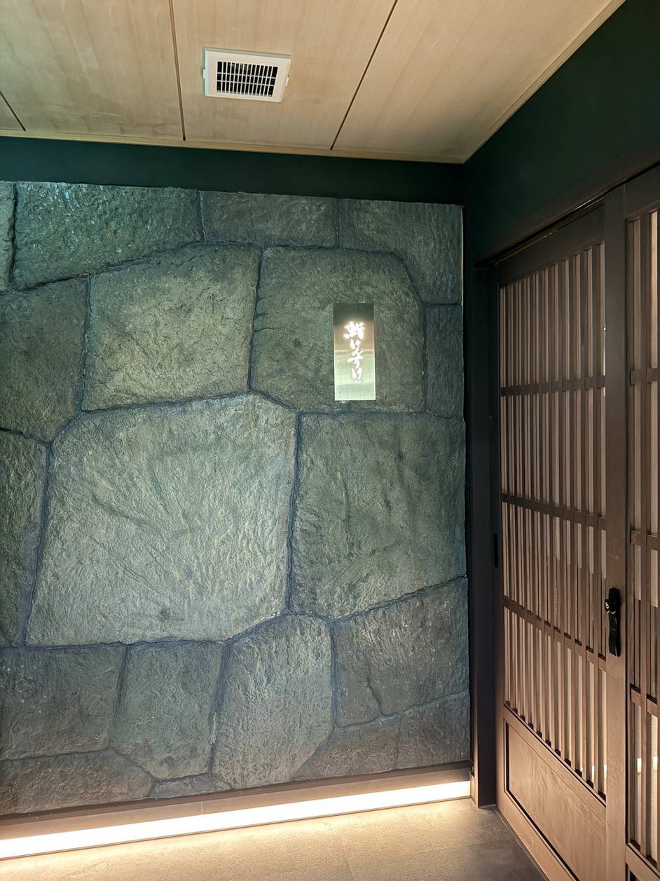 Stone-walled entrance with wooden sliding doors at Sushi Kensuke in Azabu-Juban