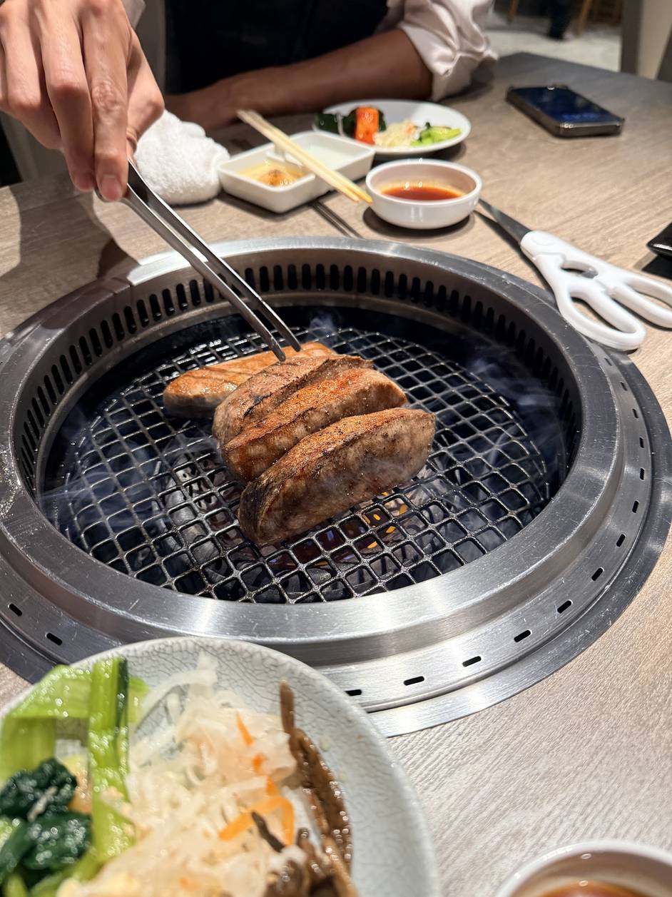 Grilling a thick cut of wagyu with tongs over charcoal