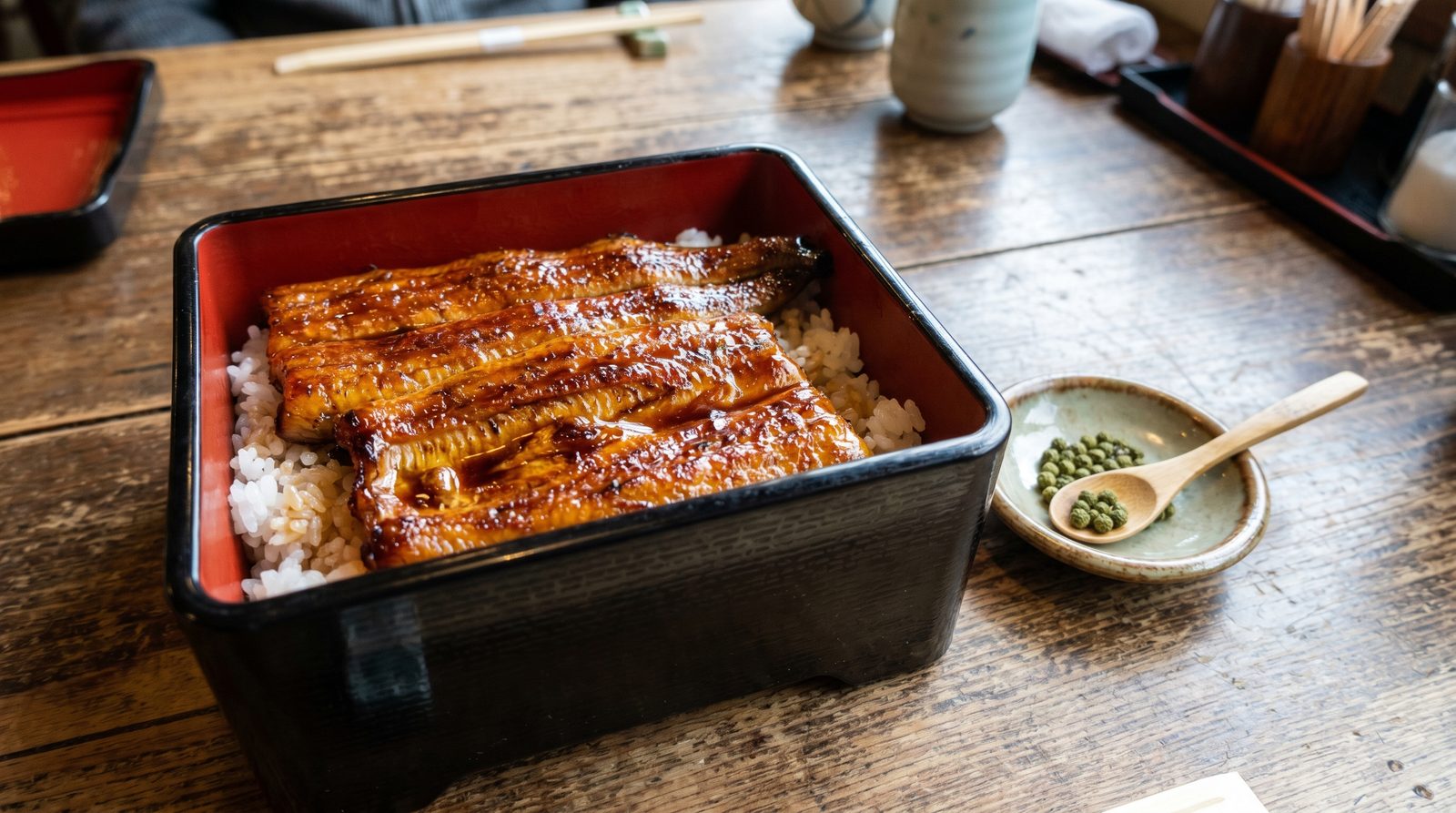 Unaju grilled unagi eel over rice in a black lacquered box with sansho pepper