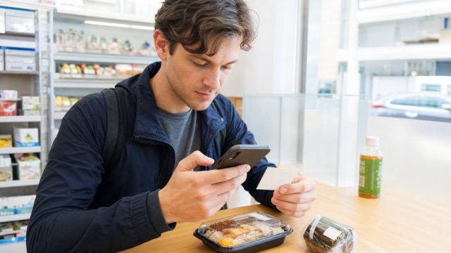 Photo-real AI image of a traveler checking a Japanese food label and allergy card before eating.