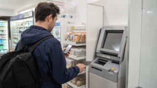Traveler checking a declined foreign card at an ATM inside a Japanese convenience store