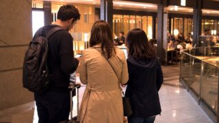 Tourists checking dinner options near a Tokyo station after a failed restaurant reservation.