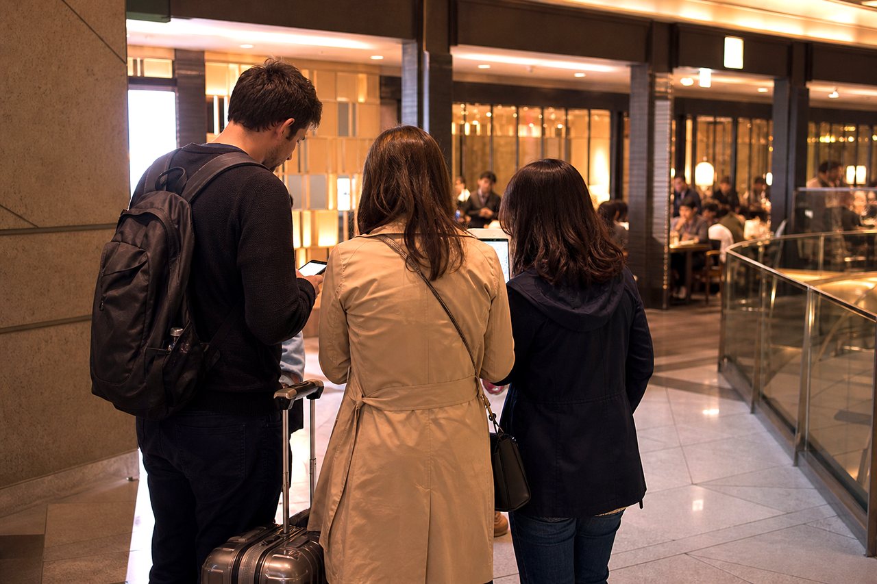 Tourists checking dinner options near a Tokyo station after a failed restaurant reservation.