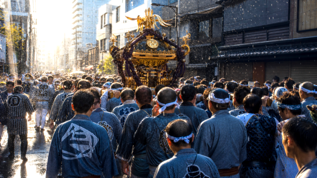 Mikoshi carriers and spectators on a wet Tokyo summer festival street.