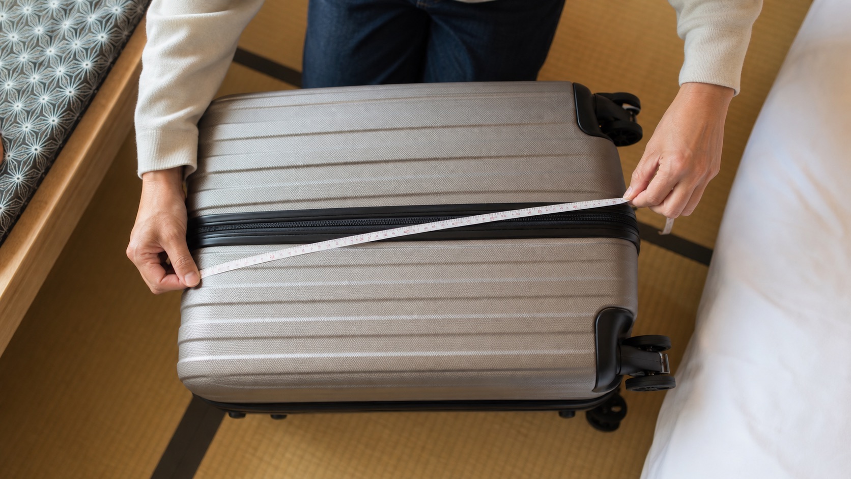Traveler measuring a suitcase before using a Japanese luggage delivery service