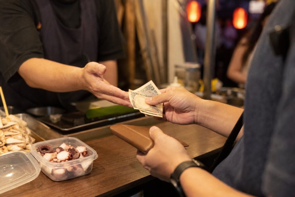 Visitor pays with small yen notes while keeping a backup payment method