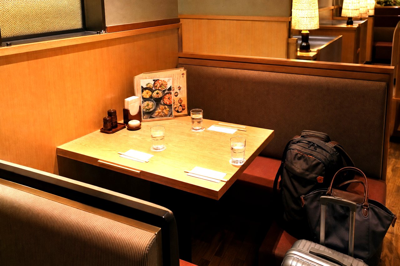 Japanese family restaurant booth with luggage beside the table as a seated backup meal option.