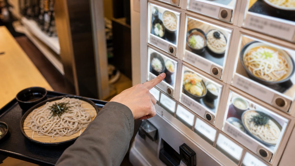 Traveler choosing soba from a ticket machine with photo menu buttons