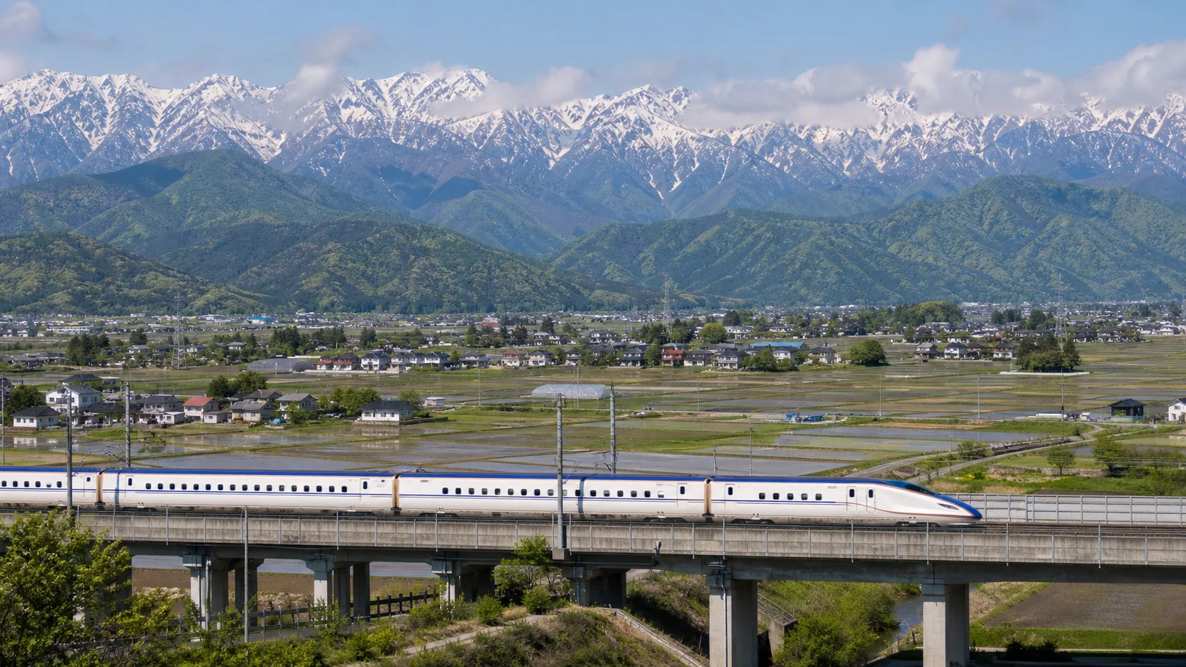 Shinkansen traveling through Nagano with the Japanese Alps in the background