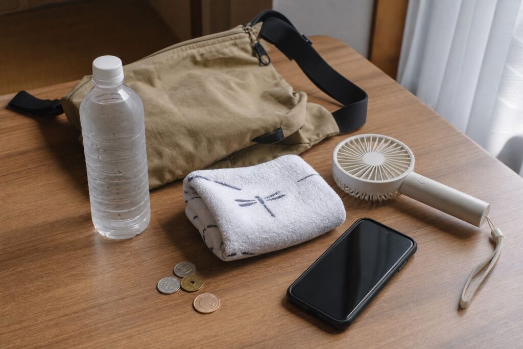 Summer festival heat kit with water, towel, fan, phone and small bag