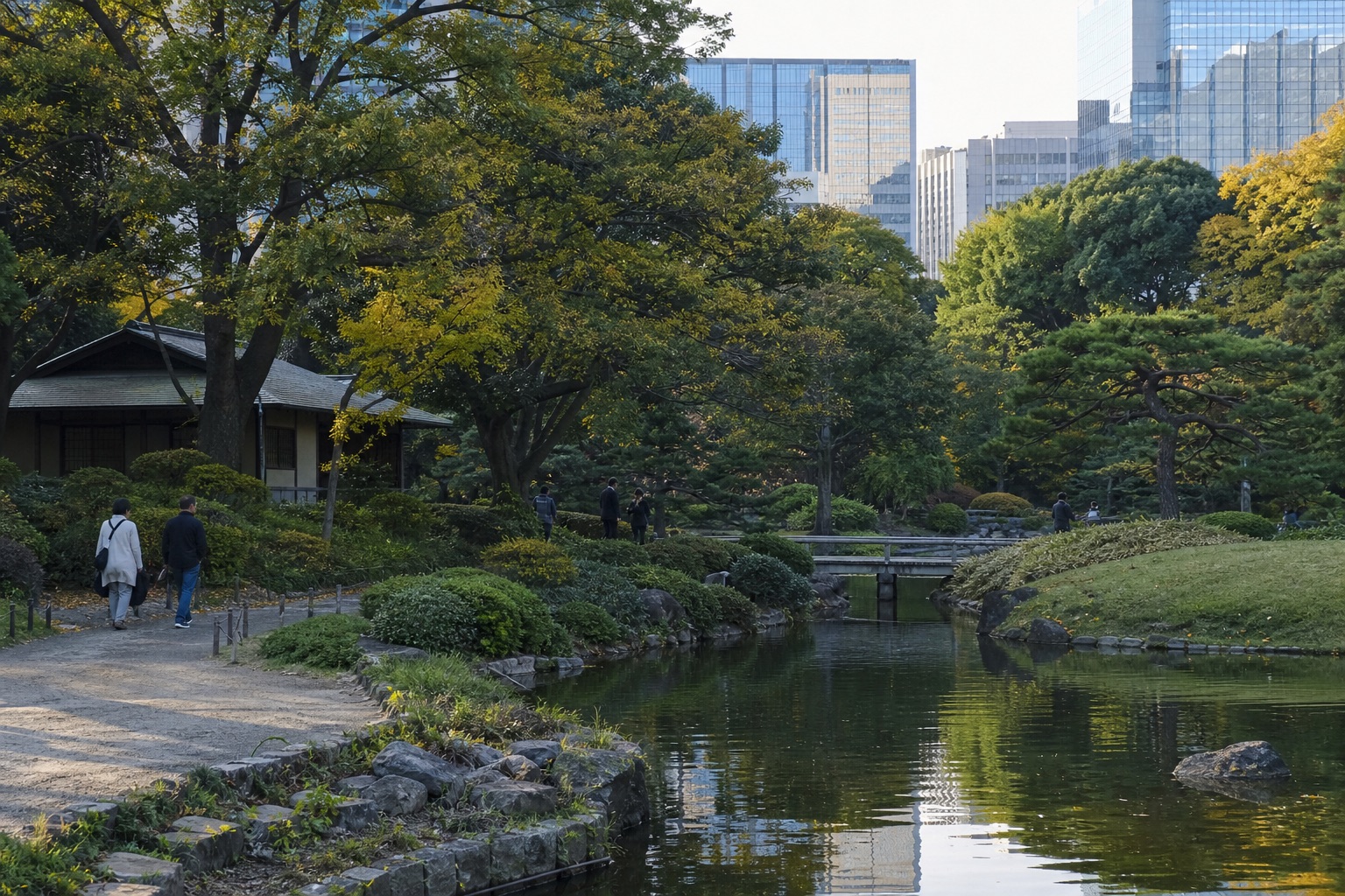 Central Tokyo garden in late October with mostly green trees and a small amount of yellow foliage