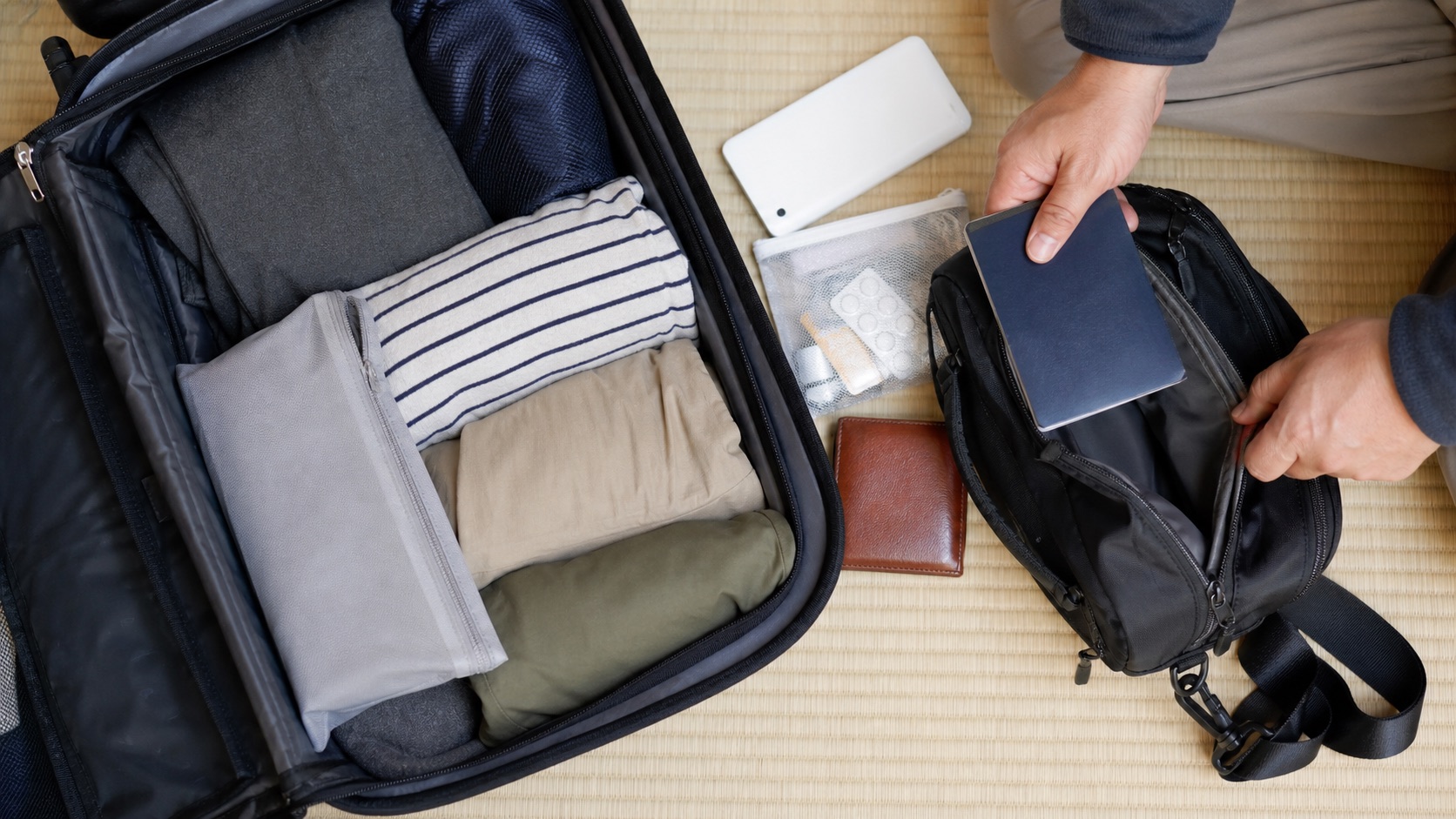 Traveler moving passport and essentials from a suitcase to a day bag