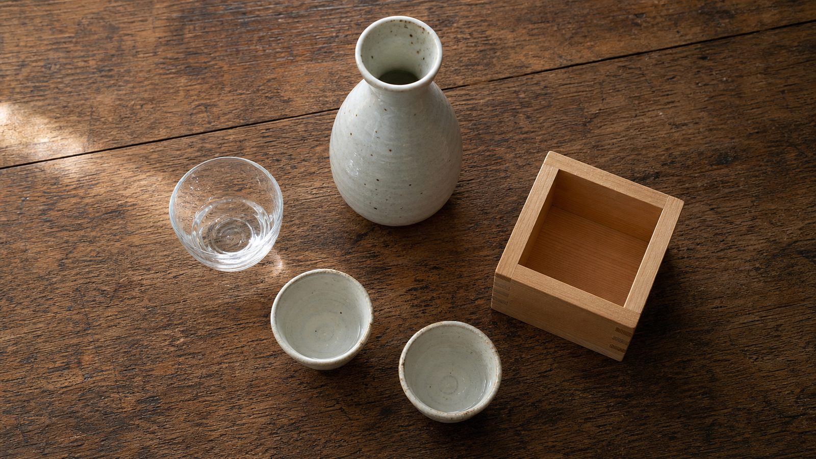 Sake glass, tokkuri, ochoko cups and wooden masu on a Japanese counter