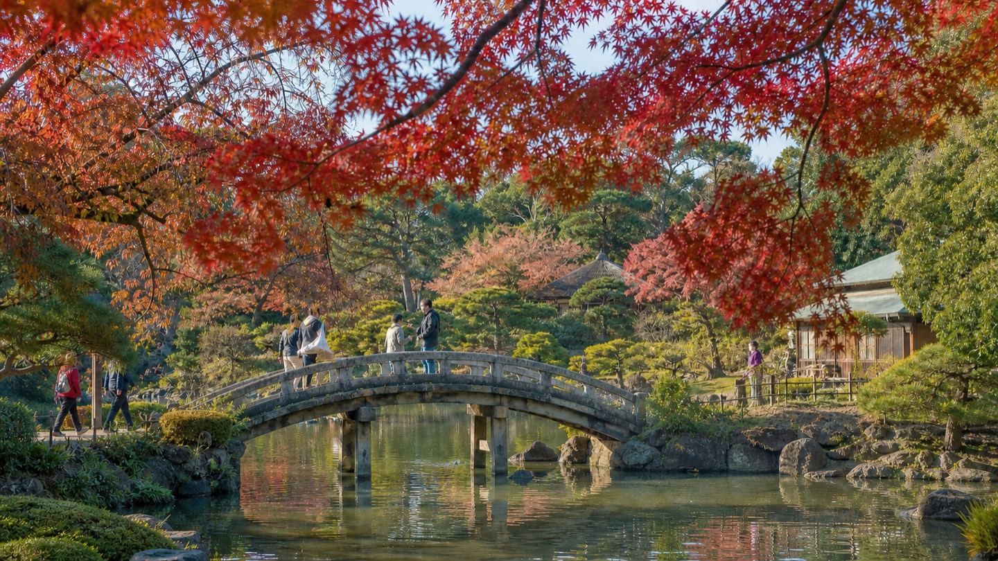 Red and orange maple leaves framing a bridge and pond in Koishikawa Korakuen