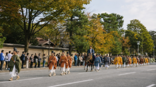 Autumn cultural procession moving along a broad Kyoto street while visitors watch from the curb