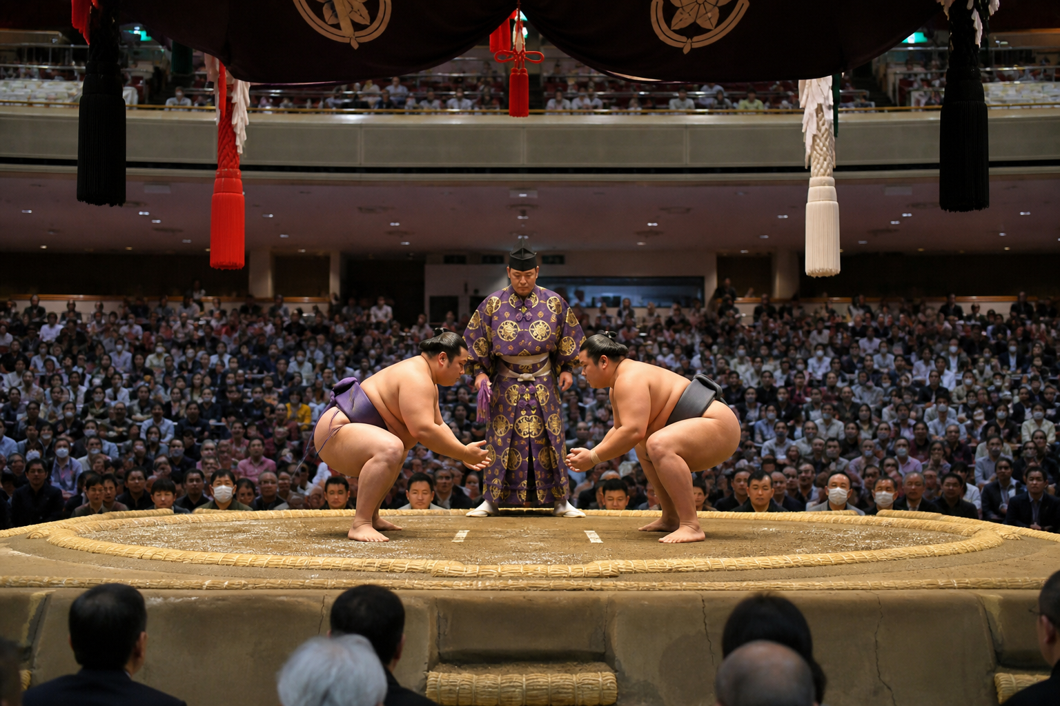 Two sumo wrestlers preparing to begin a bout in a Japanese arena