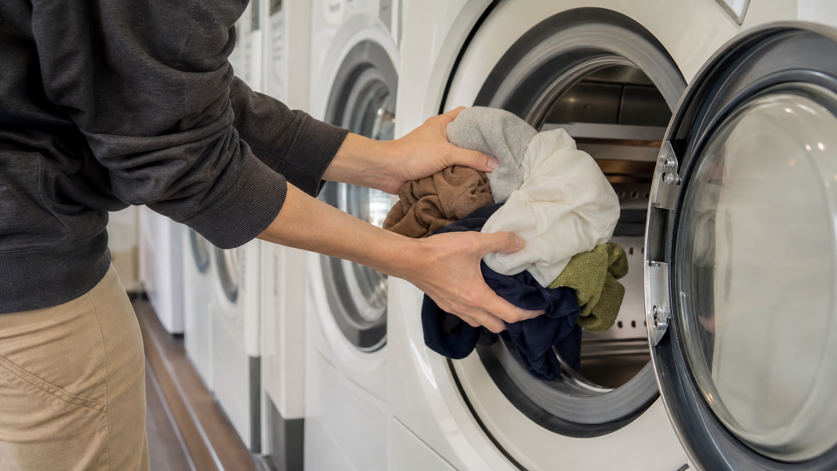 Traveler loading ordinary clothes into a front-loading laundromat machine