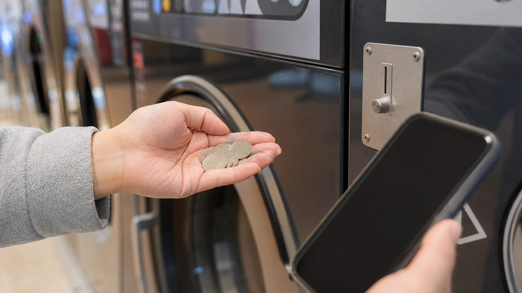 Japanese coins and a phone beside a laundromat payment panel