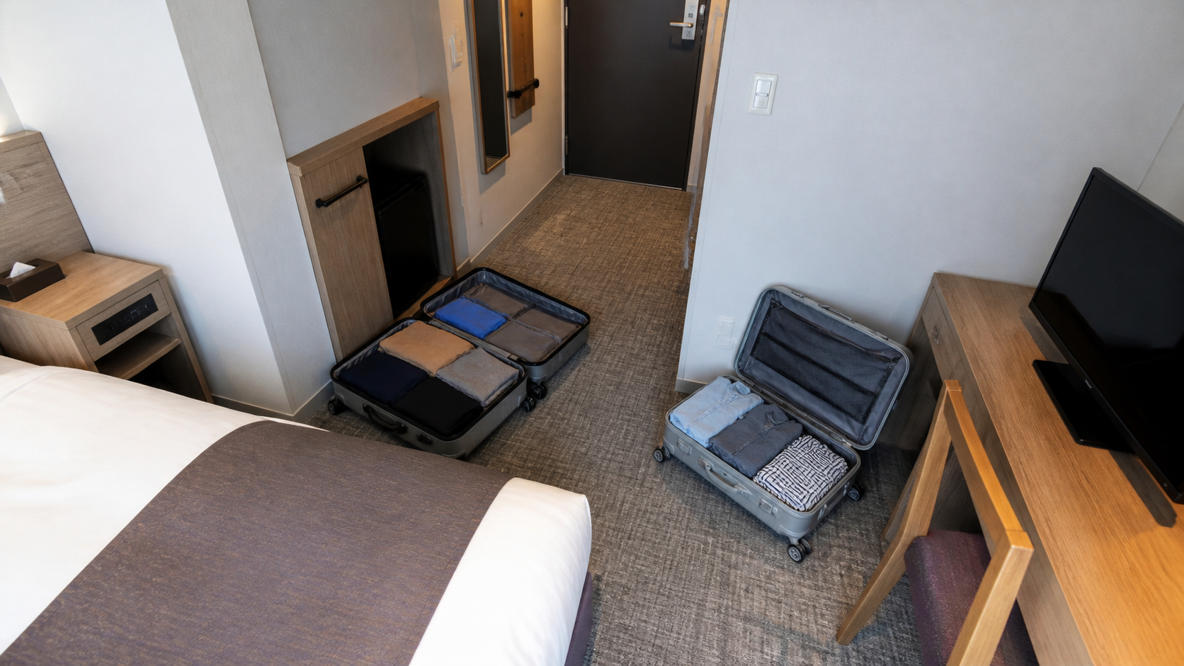 Overhead view of two open large suitcases in a hotel room without blocking the entrance