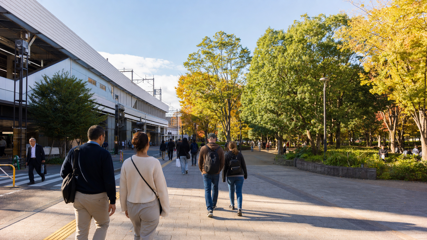 Visitors walking from a Tokyo station toward a green park in autumn