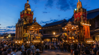 Two traditional Kawagoe dashi floats facing each other at dusk in the storehouse district