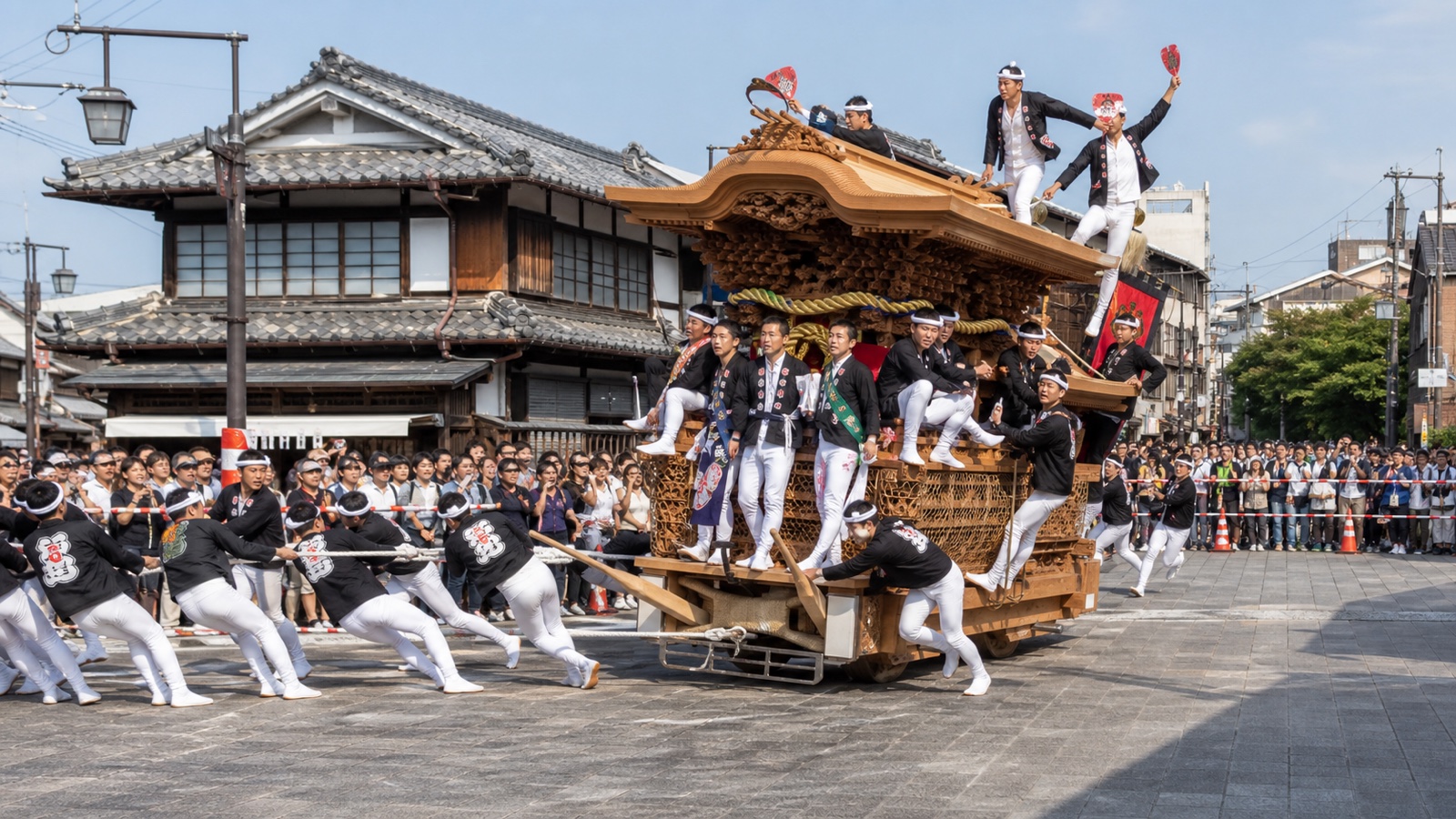 A carved Kishiwada danjiri turning through a traditional street as spectators watch from behind a safety line