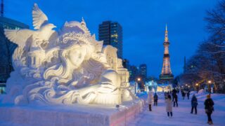 Large snow sculptures in Odori Park with Sapporo TV Tower at blue hour
