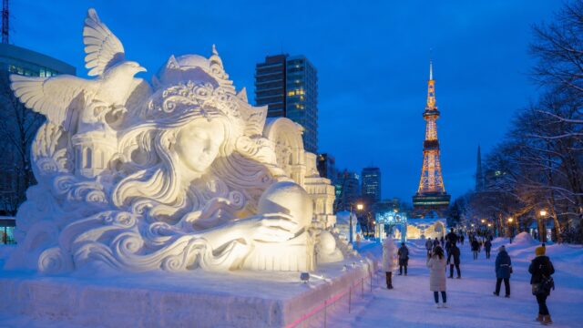 Large snow sculptures in Odori Park with Sapporo TV Tower at blue hour