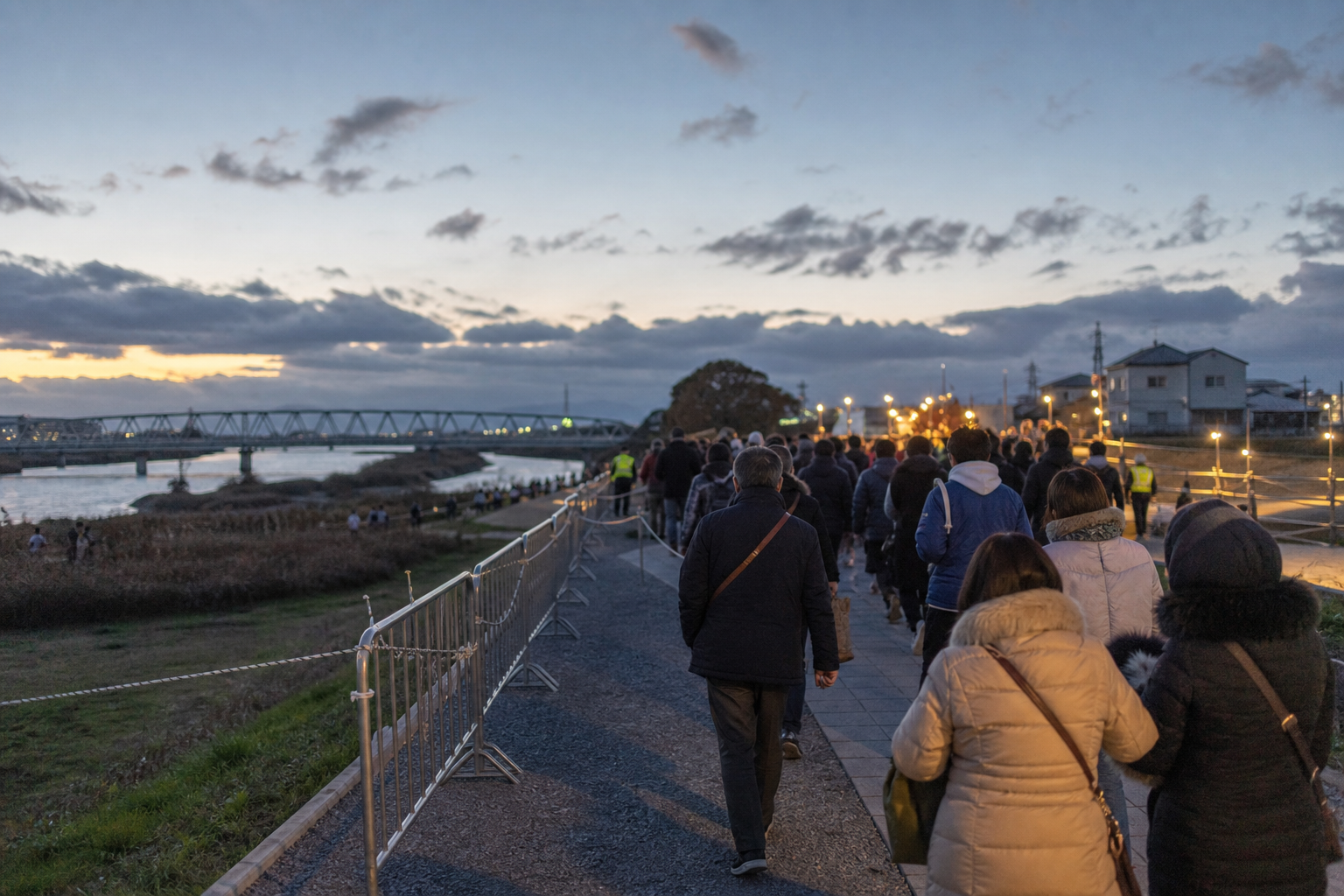 Travelers walking along a managed riverside approach at autumn twilight