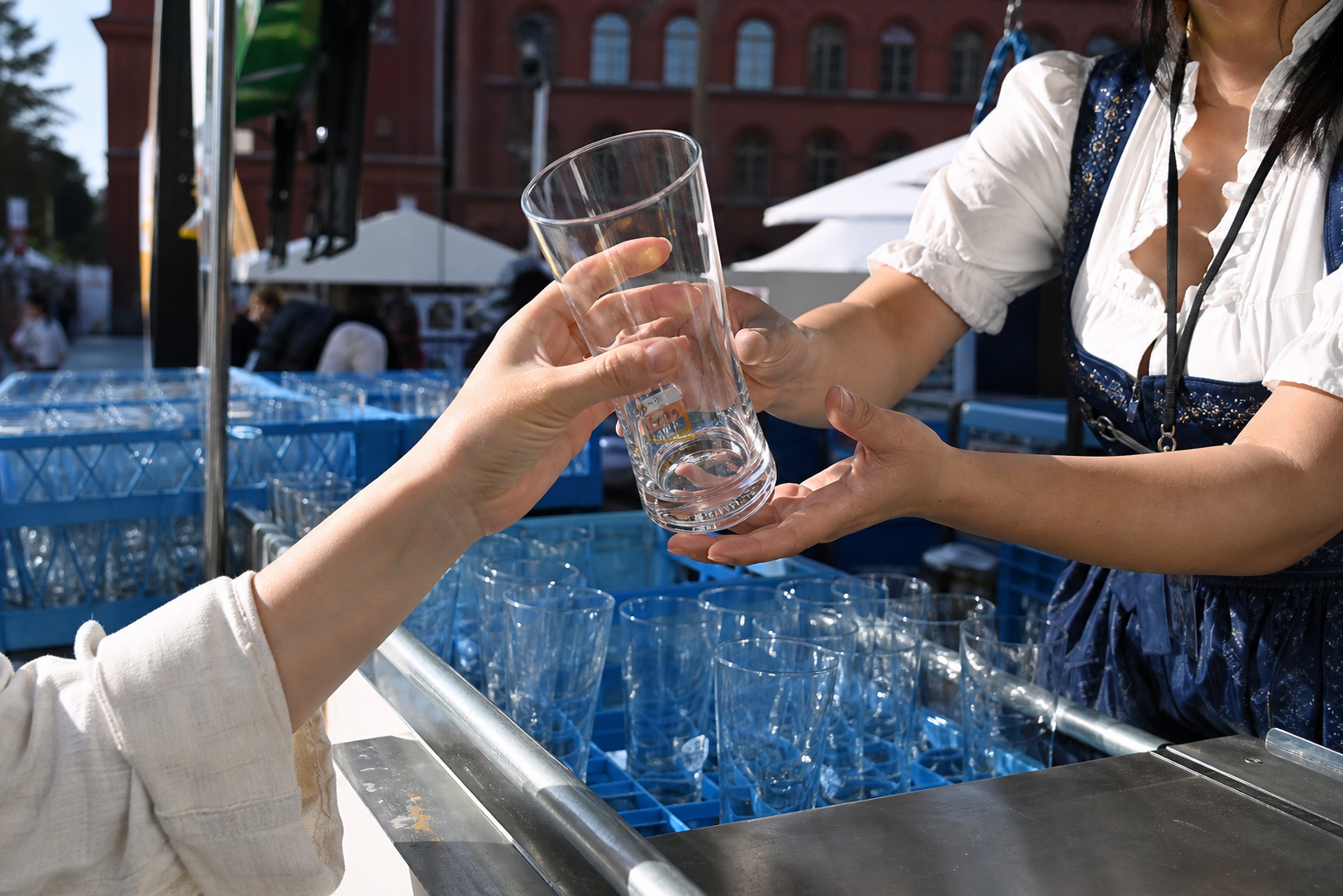 Reusable beer glass being returned at a staffed festival counter