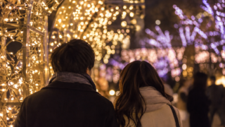 Two visitors in coats looking toward generic golden and violet lights